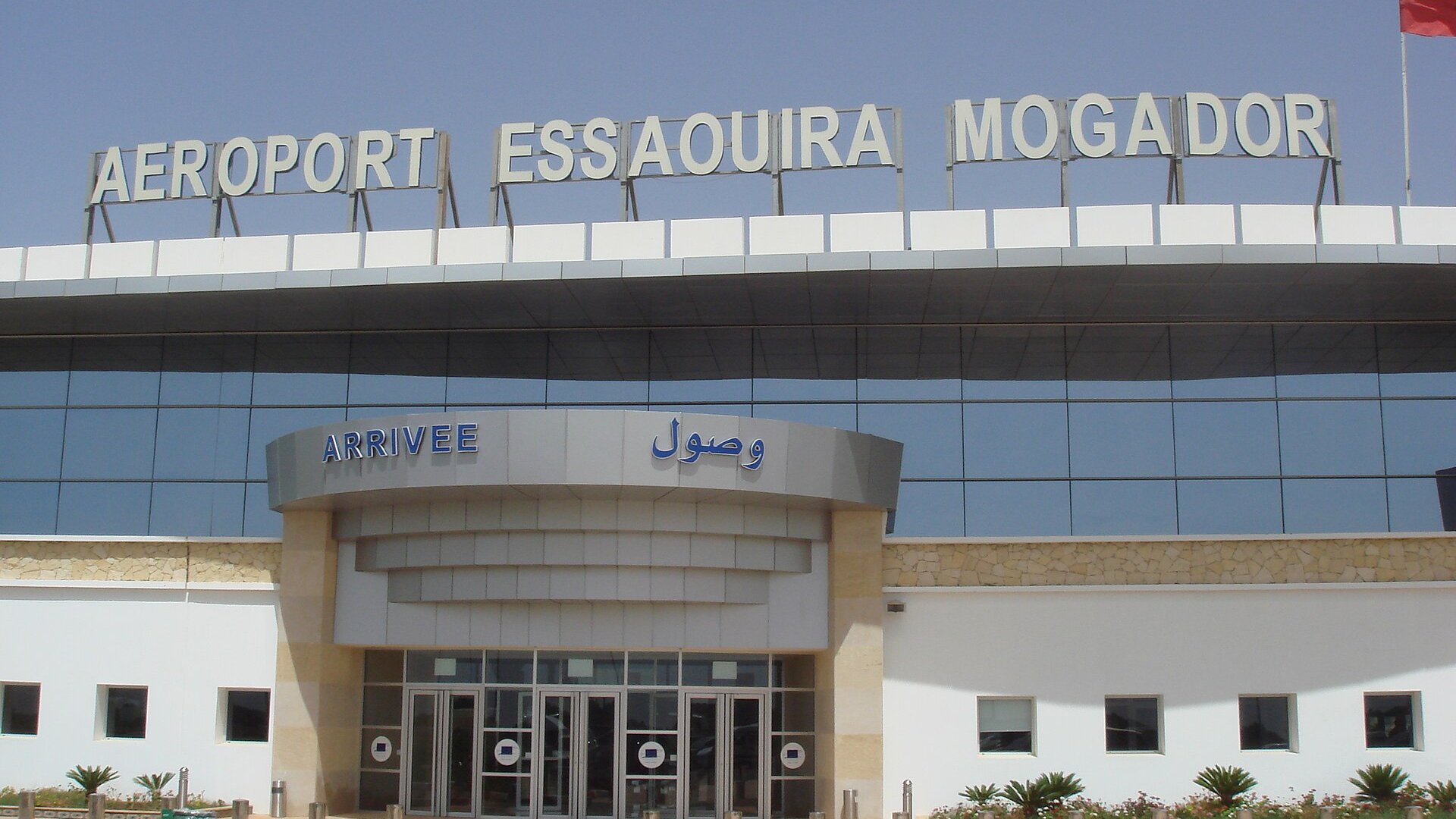 The arrivals entrance of Essaouira-Mogador airport in Morocco under a sign reading Aeroport Essaouira Mogador