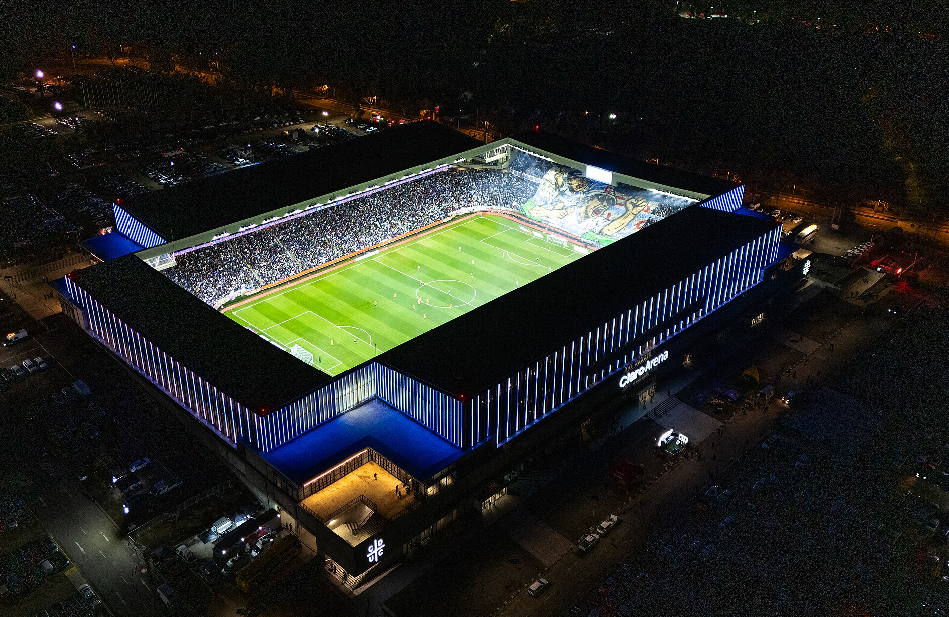 Night aerial view of the illuminated Claro Arena football stadium and surrounding streets in San Carlos de Apoquindo