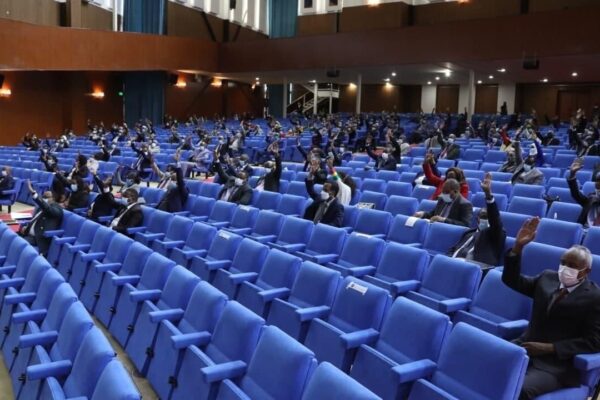 Members of Ethiopia's House of Peoples' Representatives in blue seats raise their hands during a vote
