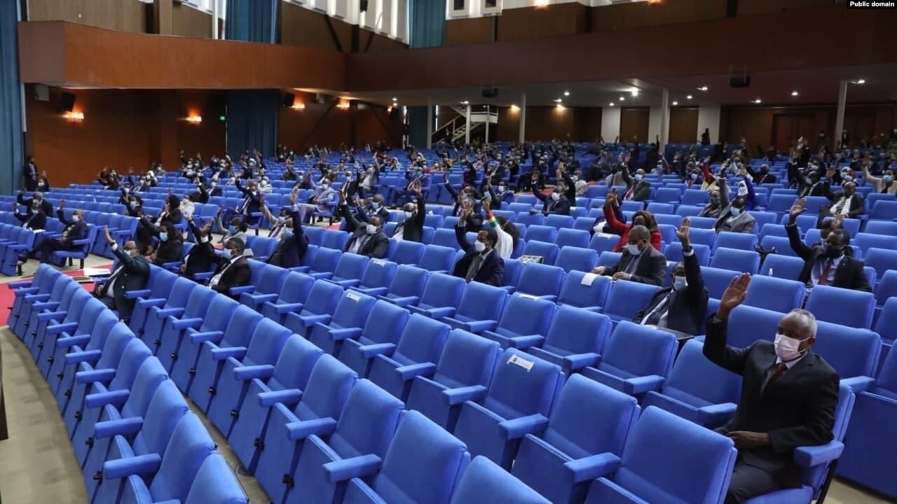 Members of Ethiopia's House of Peoples' Representatives in blue seats raise their hands during a vote