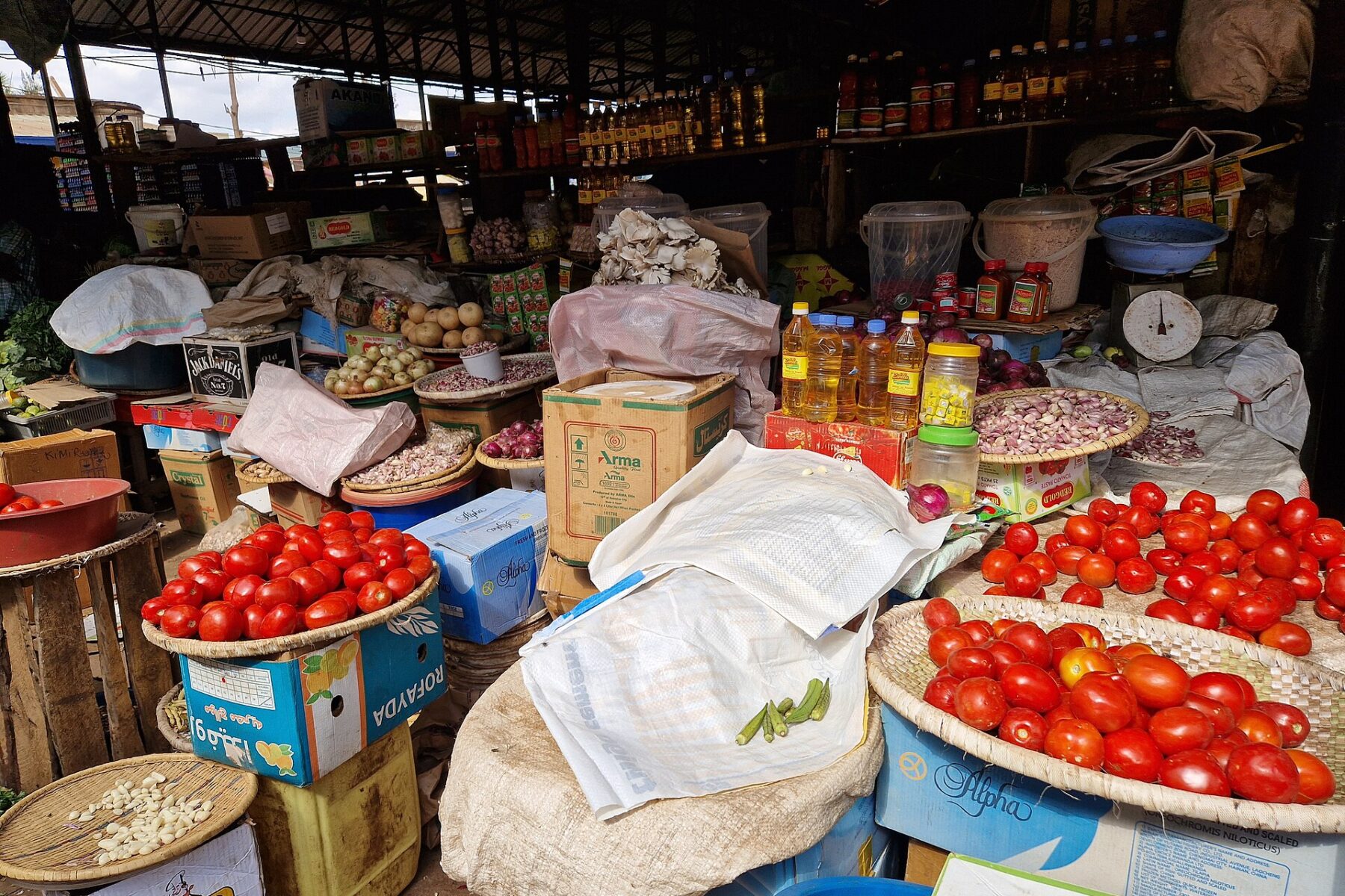 Tomatoes, onions, cooking oil and dry goods stacked at a stall in Kimironko market, Kigali