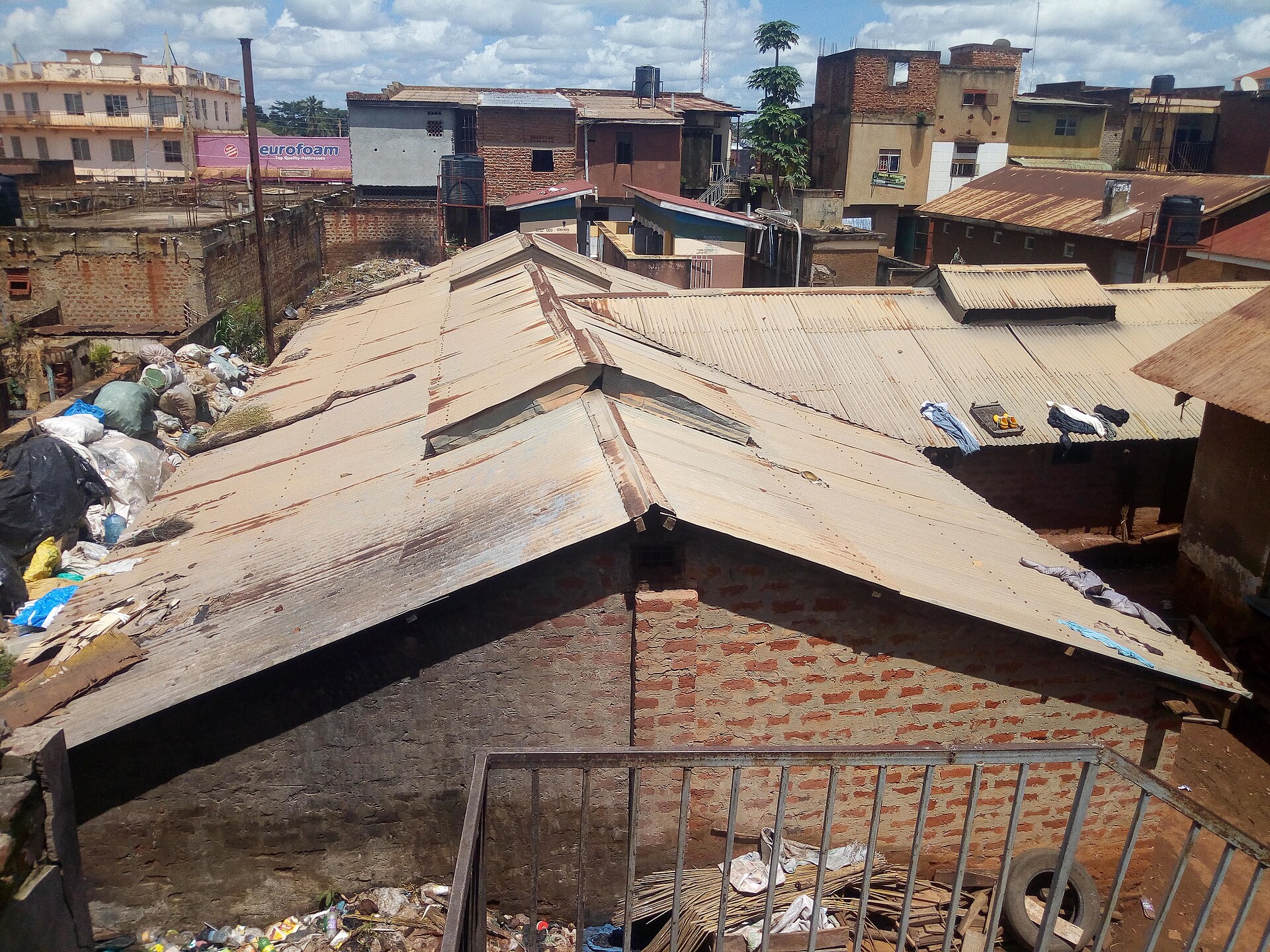 Rusty corrugated iron roofs of a low brick building surrounded by houses in Gulu town, northern Uganda
