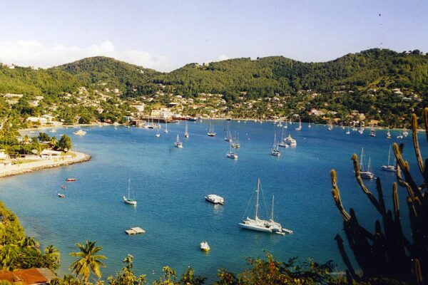 Sailboats anchored in the blue waters of Admiralty Bay, with green hills and houses of Port Elizabeth on Bequia in the Grenadines