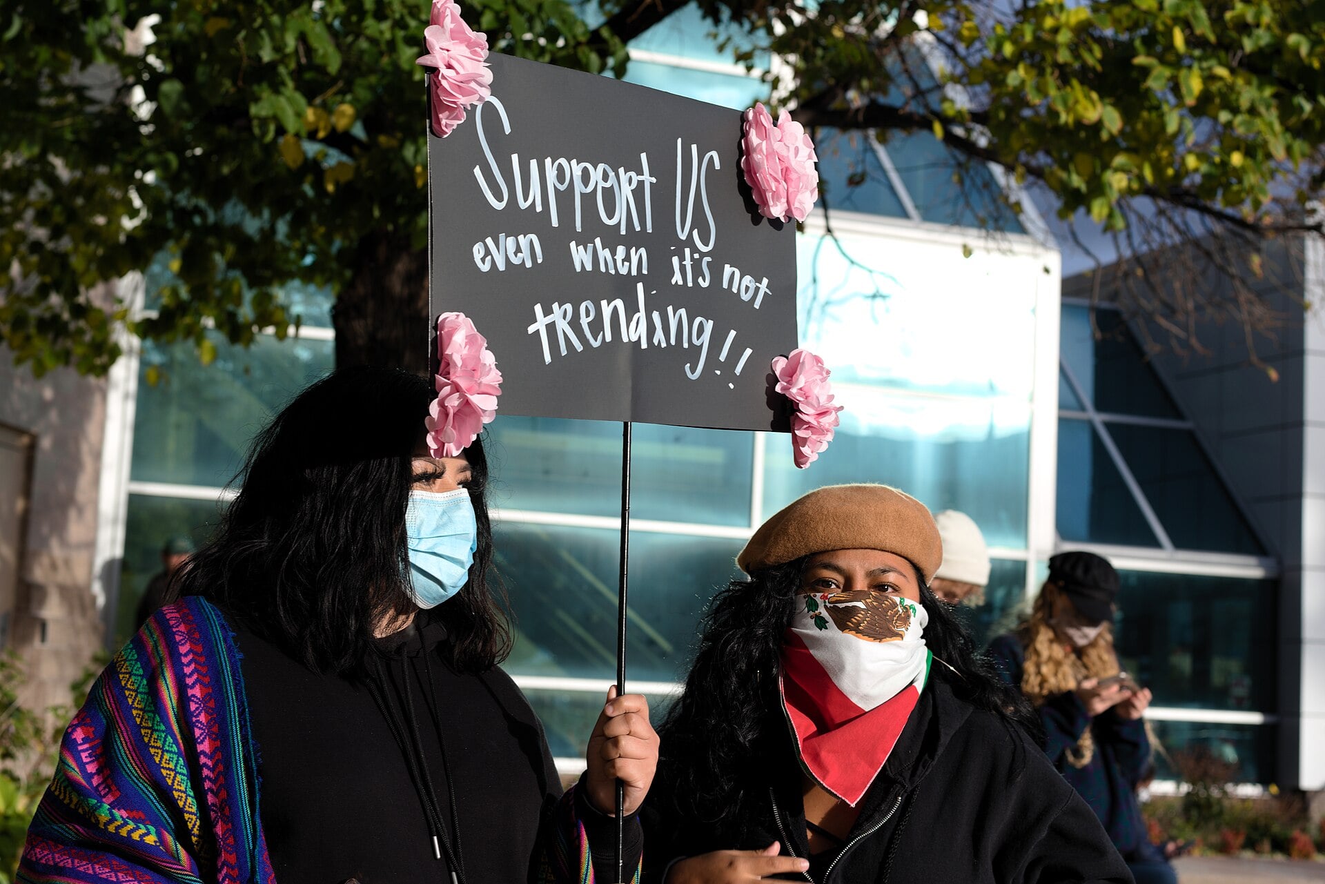 Two demonstrators hold a sign reading Support US even when it is not trending at a protest for TPS, DACA and DED recipients in Minneapolis