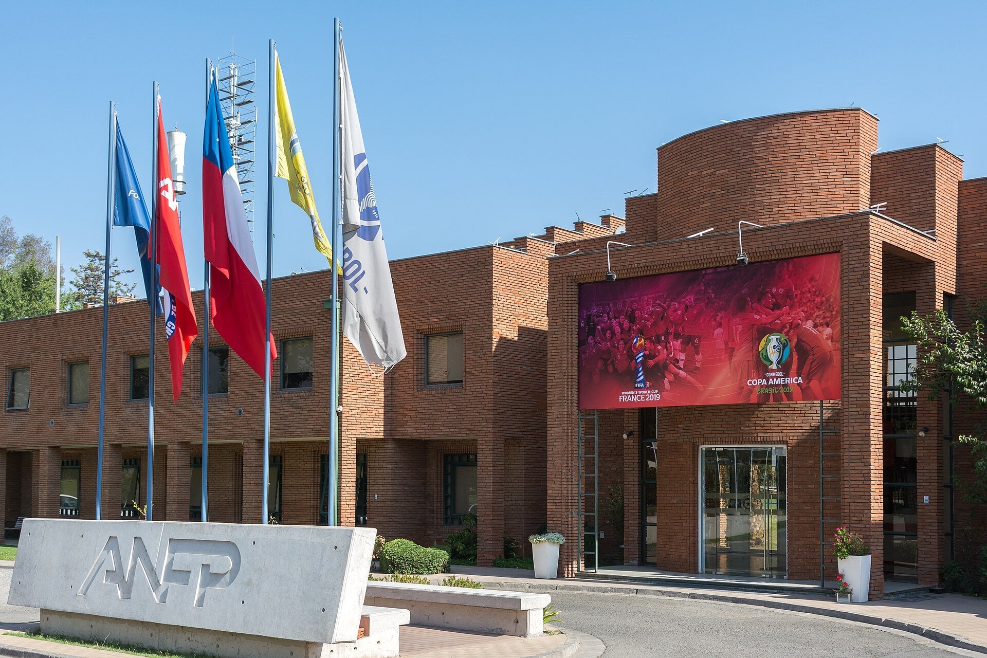Brick headquarters building of the ANFP, Chile's professional football association, with flags and the ANFP sign in front