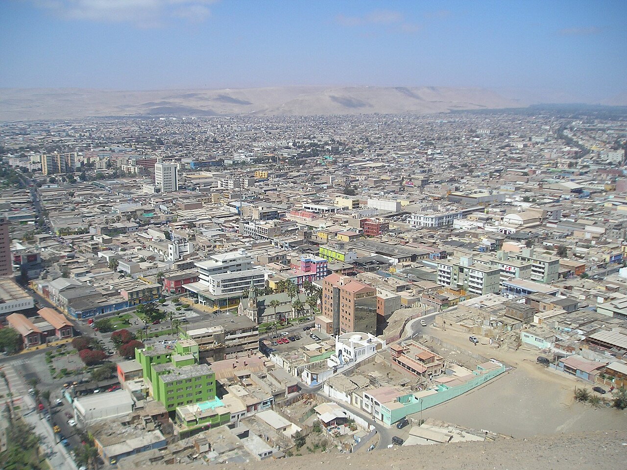 View over the city of Arica in northern Chile from a hilltop, with low buildings and desert hills in the distance