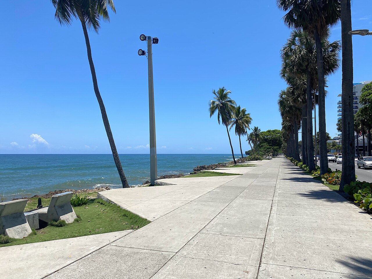 The Malecón seafront avenue in Santo Domingo with palm trees and the Caribbean Sea on a sunny day.