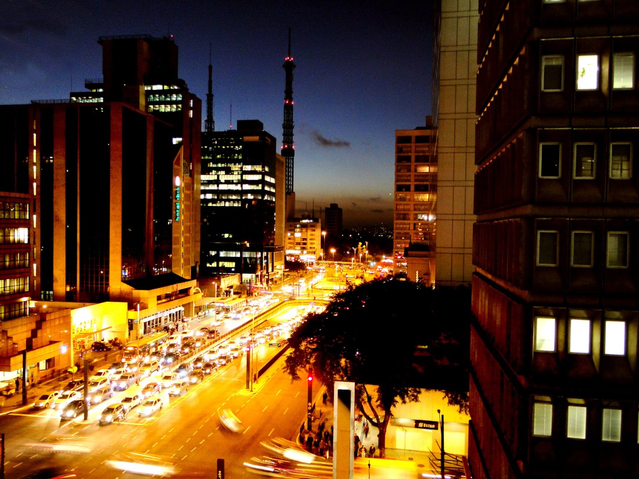 Evening traffic and lit office towers on Avenida Paulista in São Paulo