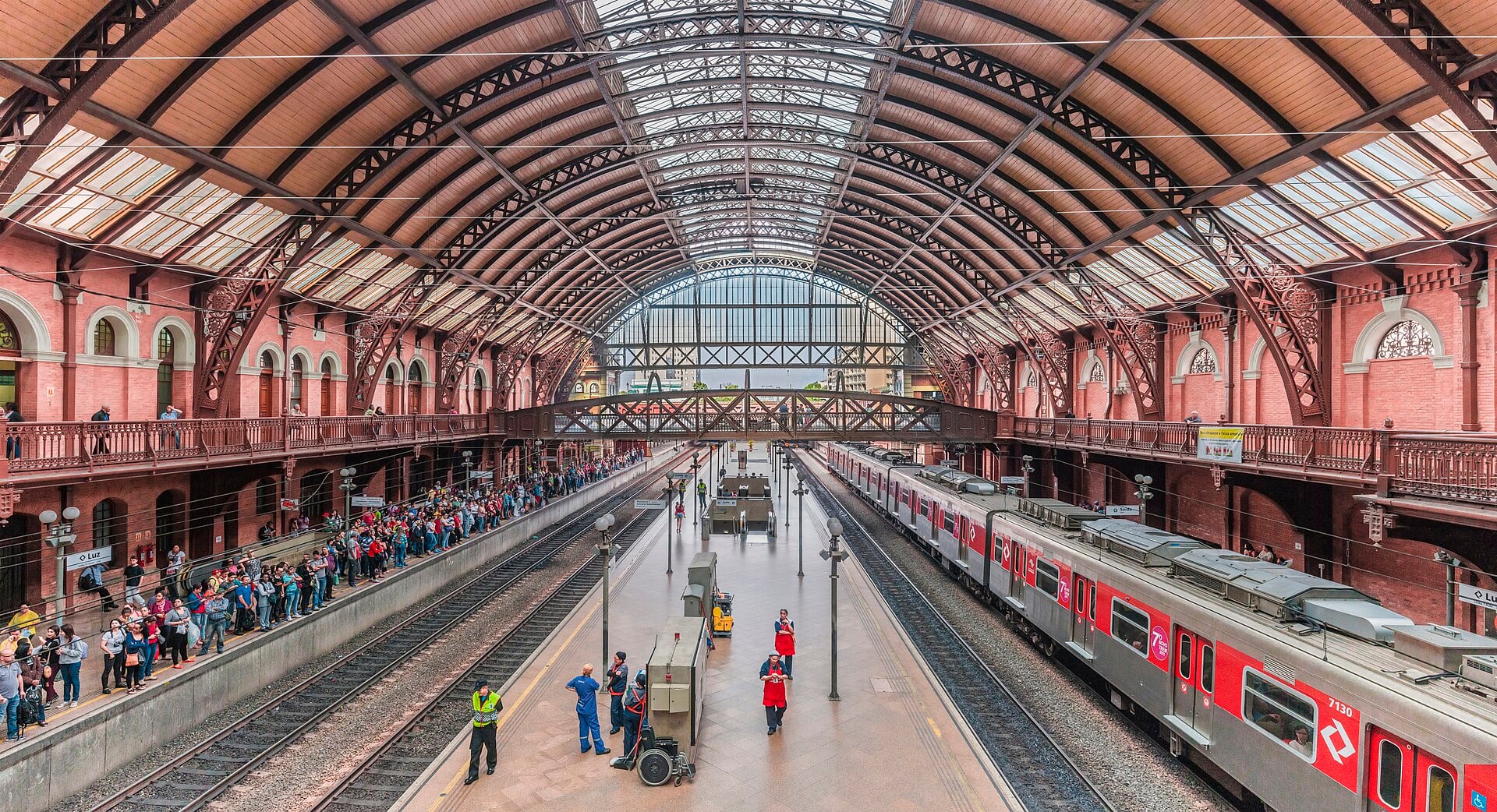 Interior of Luz station in São Paulo with its iron roof, brick walls and commuter trains