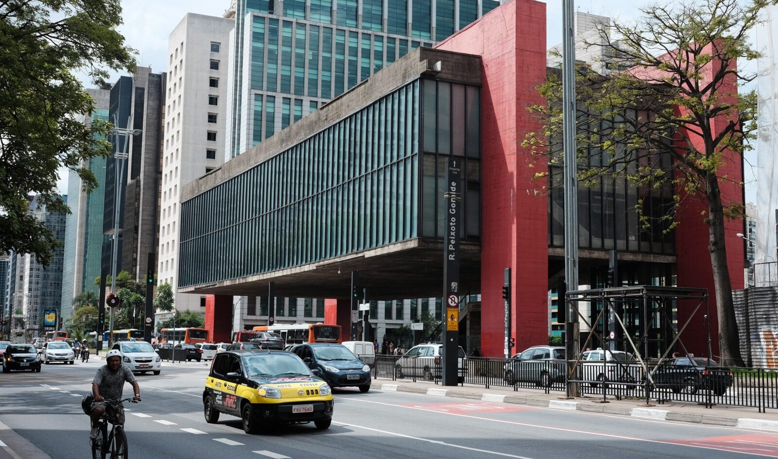 Red concrete MASP museum building on Avenida Paulista in São Paulo with a taxi and cyclist in front