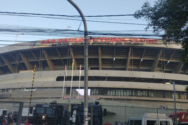 The curved concrete exterior of the Morumbi stadium in São Paulo, seen from the street behind a fence.