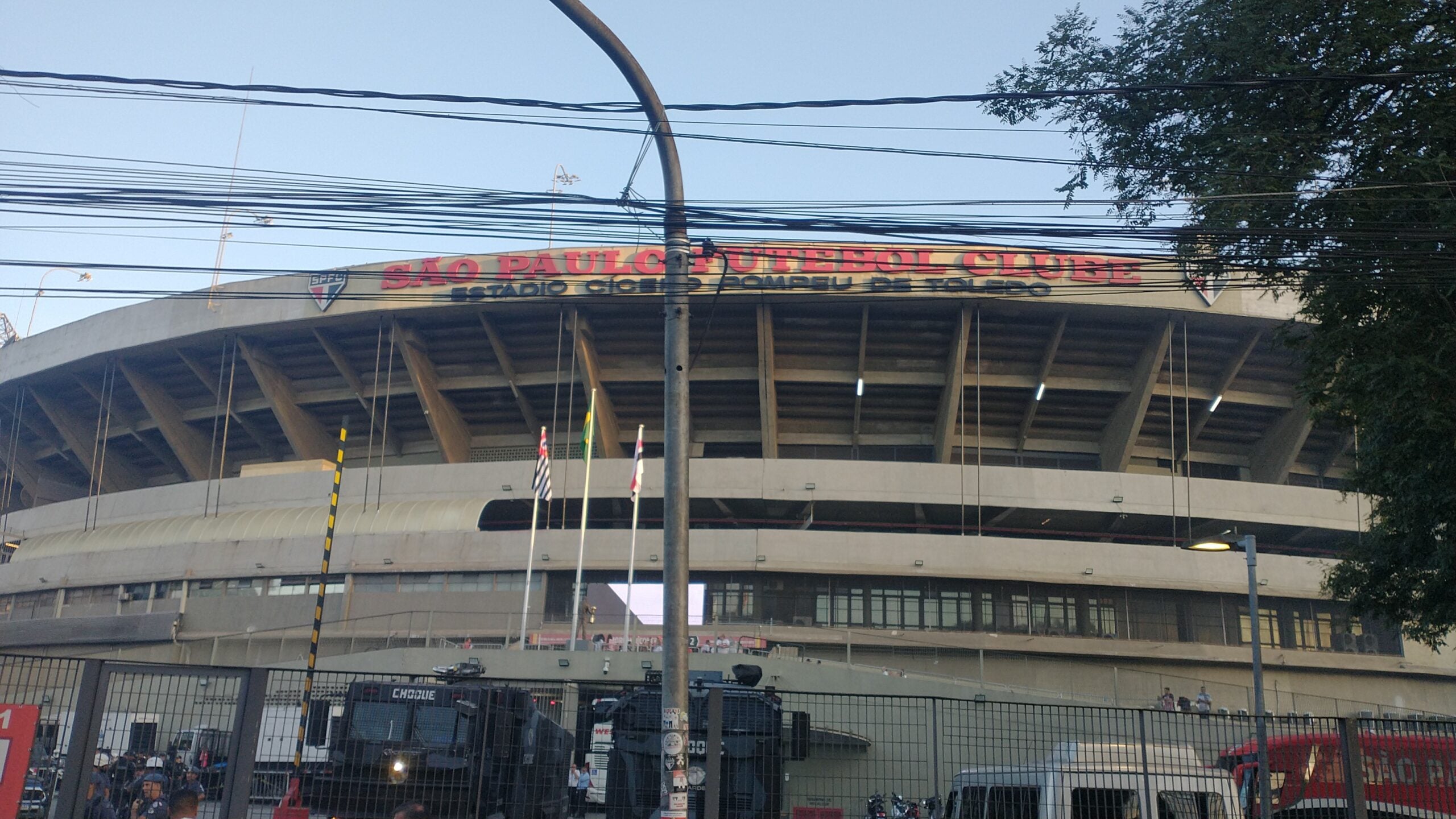 The curved concrete exterior of the Morumbi stadium in São Paulo, seen from the street behind a fence.