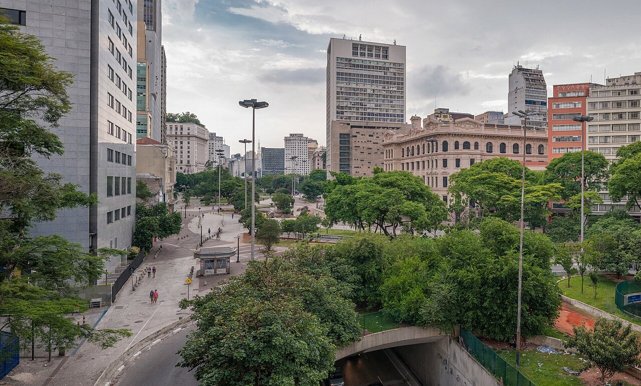 Vale do Anhangabaú in downtown São Paulo, with trees, office towers and a road tunnel entrance in the foreground