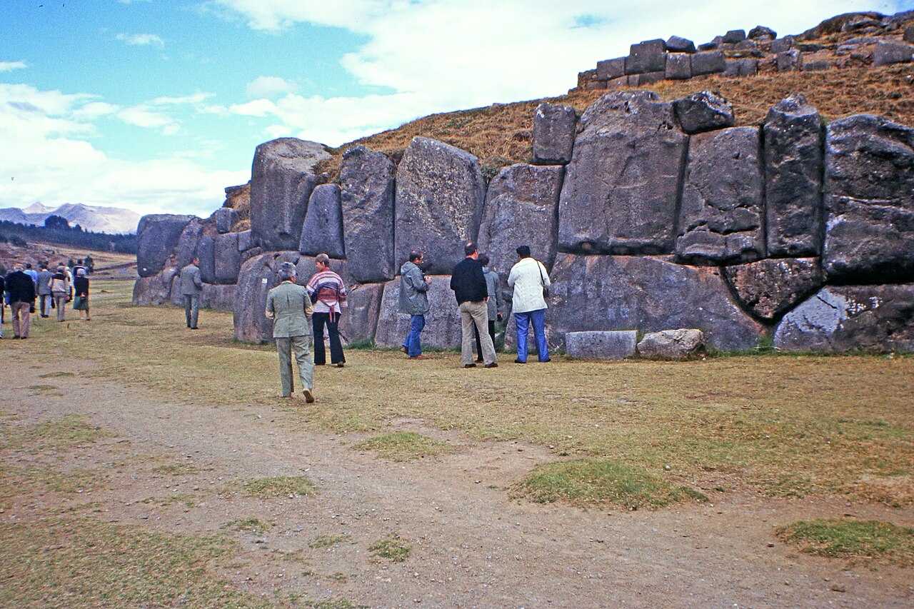 Visitors beside the giant stone walls of the Saqsaywaman fortress above Cusco, Peru.