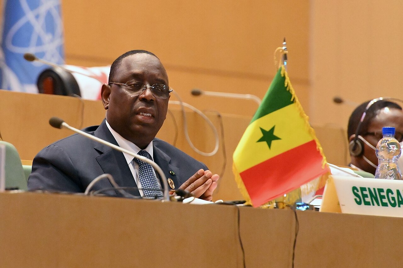 Macky Sall, former president of Senegal, speaking beside a Senegalese flag at the African Union headquarters in Addis Ababa