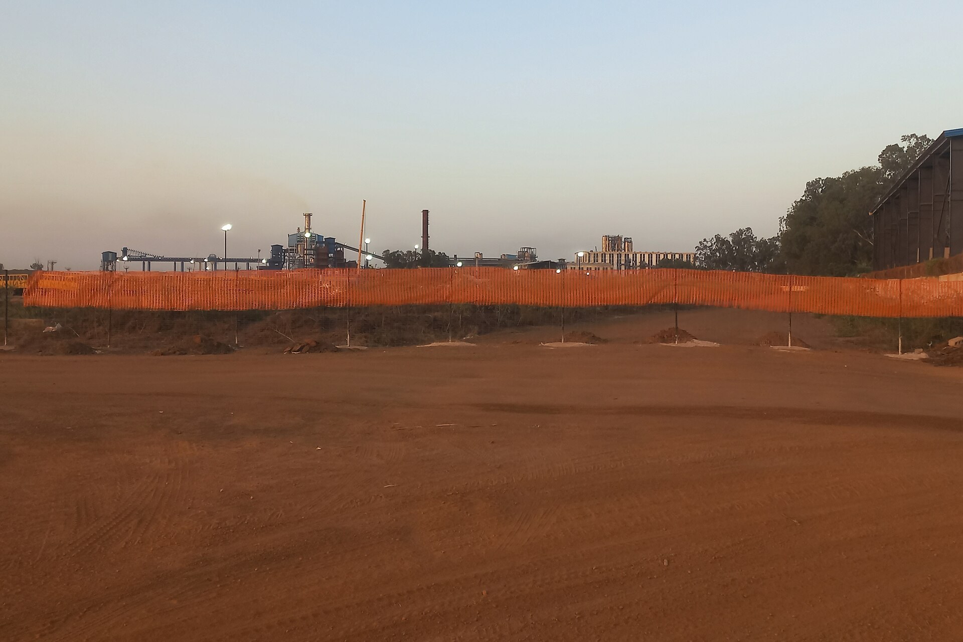 The Compagnie Sucrière Sénégalaise sugar factory at Richard-Toll seen from a distance behind an orange site fence