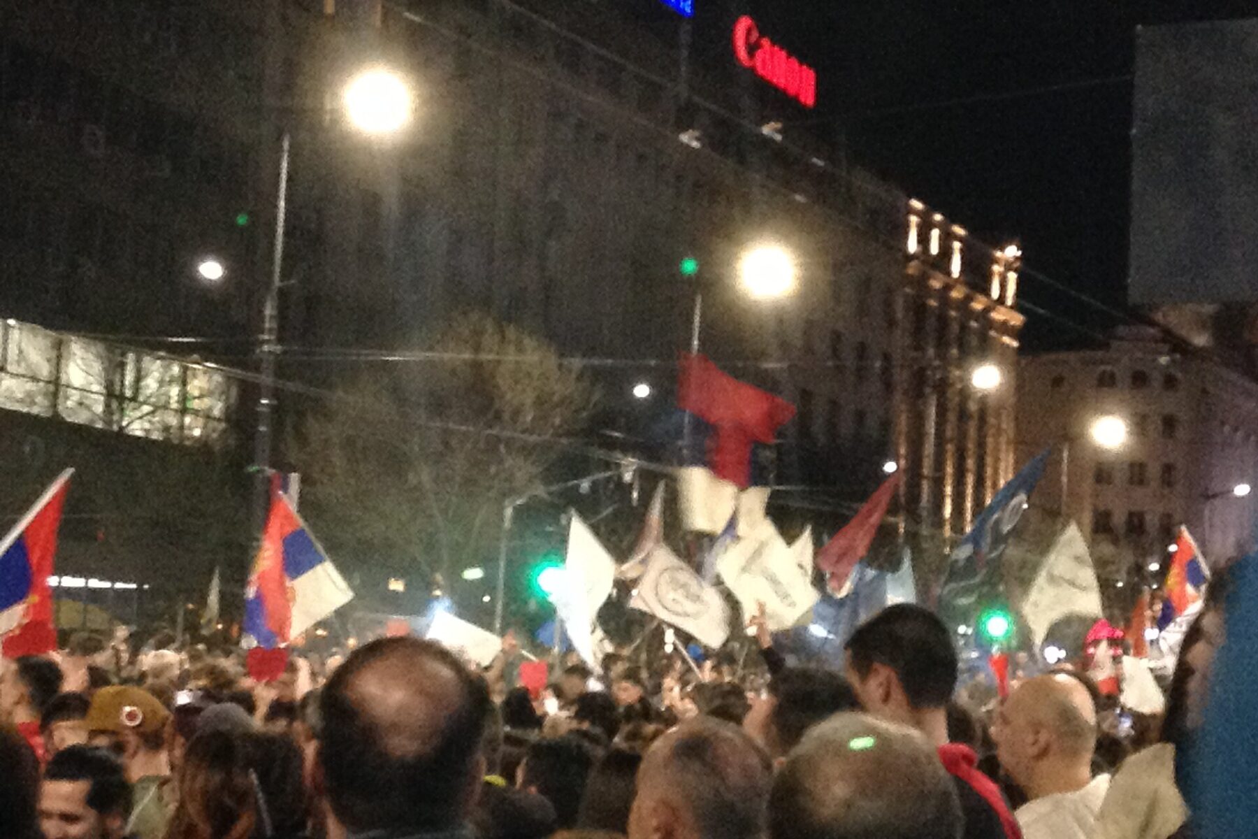 Crowd waving Serbian flags at a night protest in central Belgrade