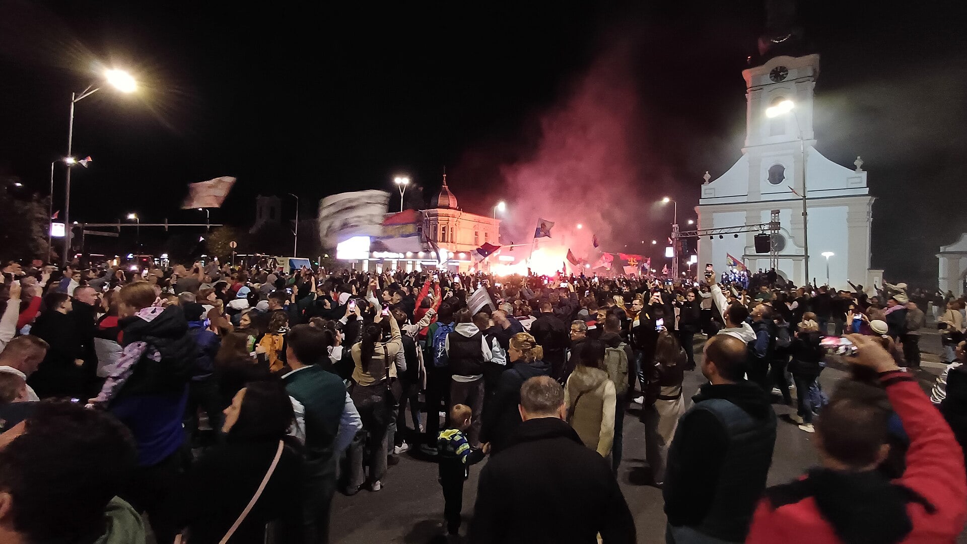 Crowd with flags and flares in the square at Stara Pazova, Serbia, at night, during a Student List event