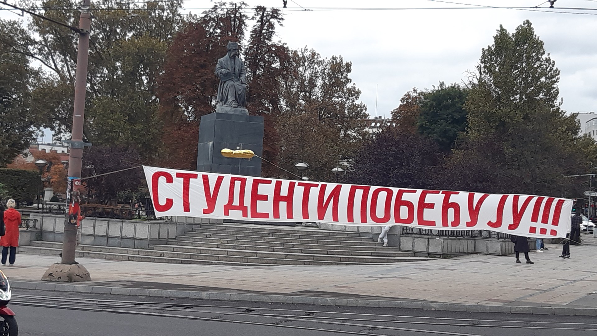 Red banner reading Students Win in Cyrillic in front of the Vuk Karadžić monument in Belgrade