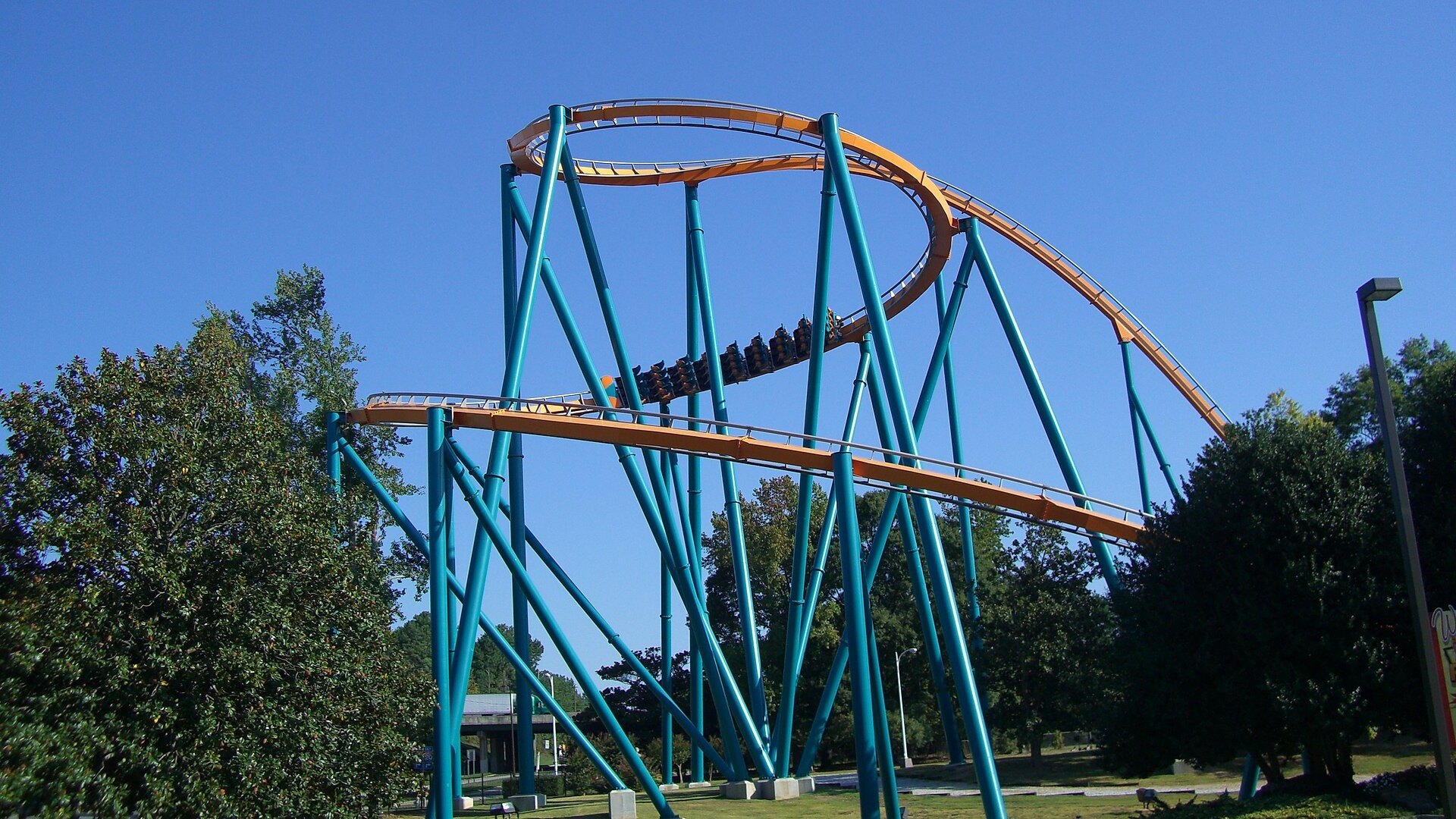 A train on the Goliath roller coaster at Six Flags Over Georgia climbing through an orange steel helix supported by teal columns, in a file photo