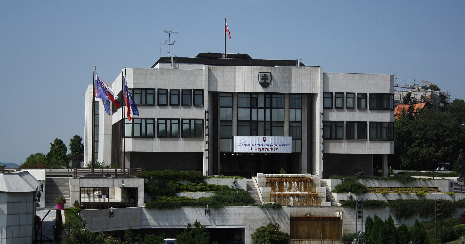 The modern white-stone National Council building in Bratislava with the Slovak and EU flags