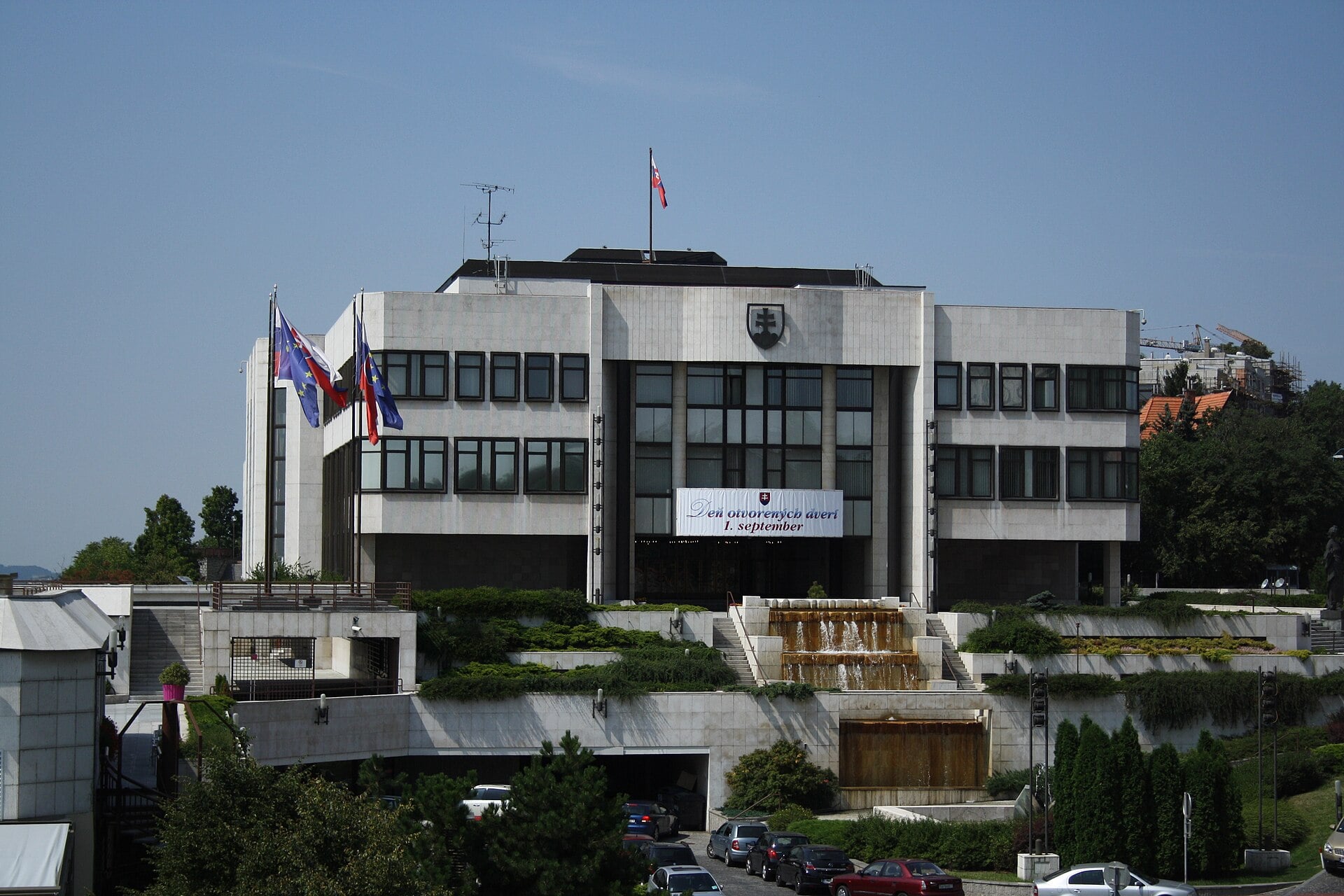 The modern white-stone National Council building in Bratislava with the Slovak and EU flags