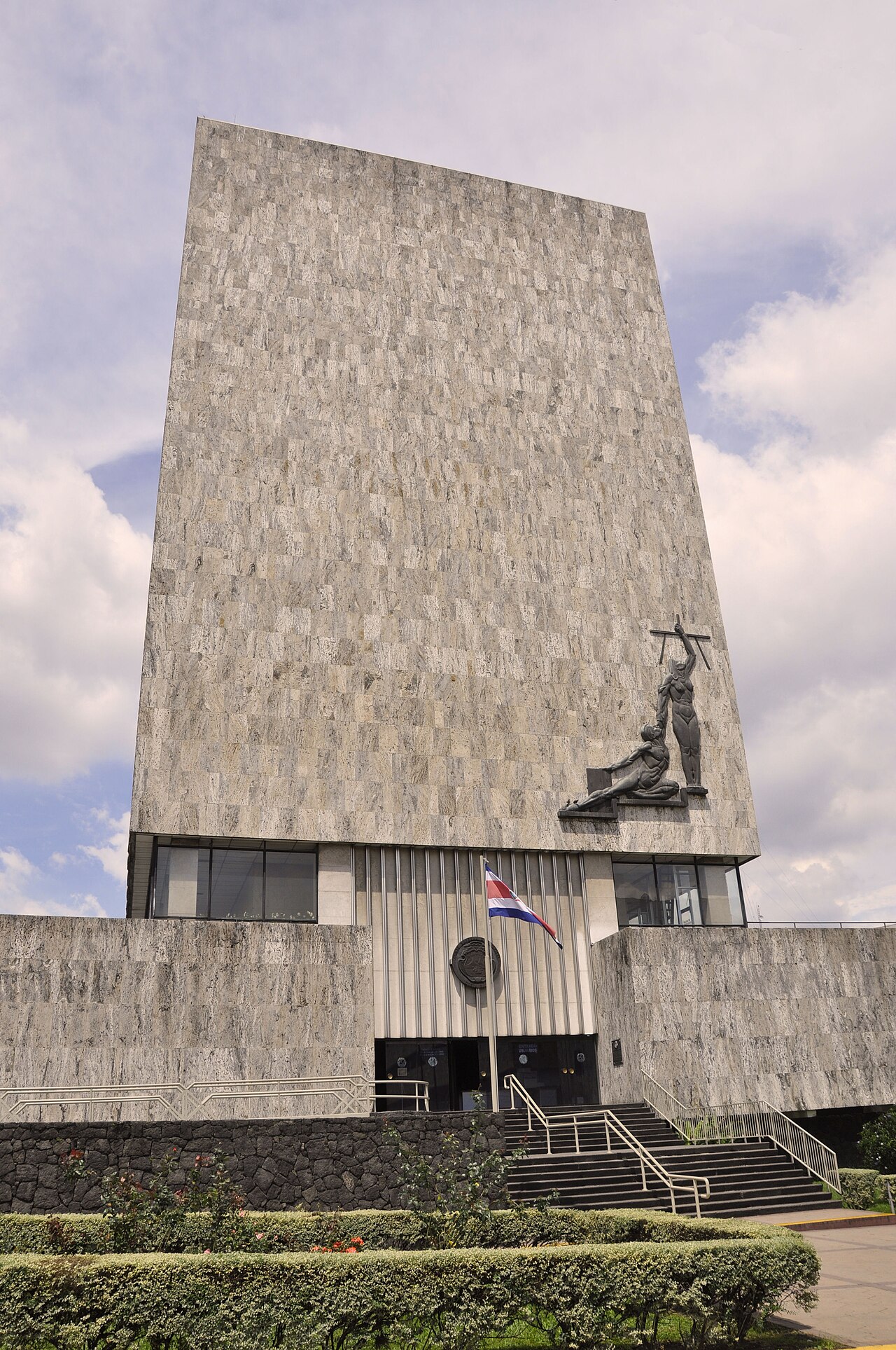 The Supreme Court of Justice building in San José, Costa Rica, with a bronze relief on its facade and the national flag at the entrance