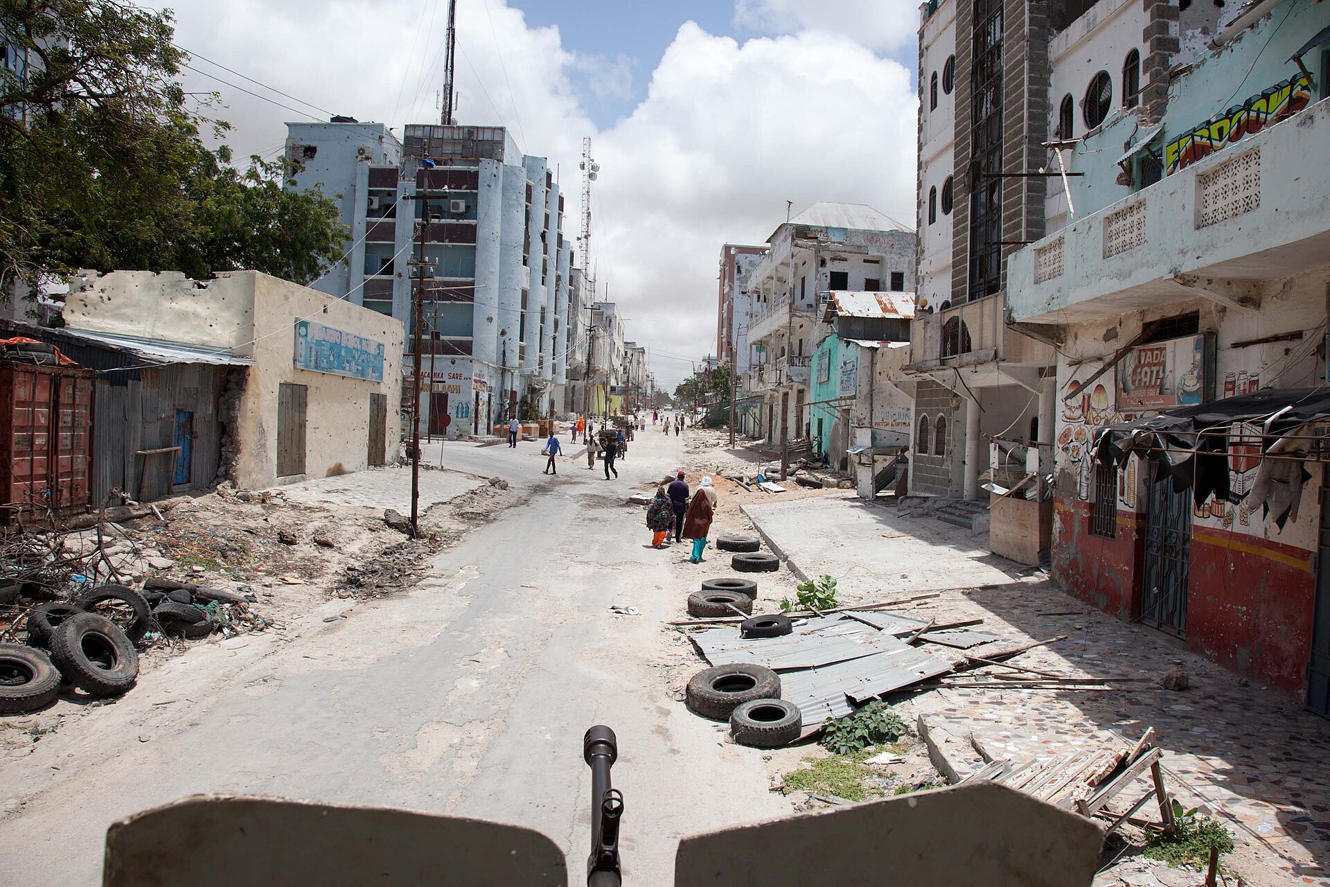 Street in Bakaara Market in Mogadishu with damaged buildings and tyres on the road, seen from an armoured vehicle