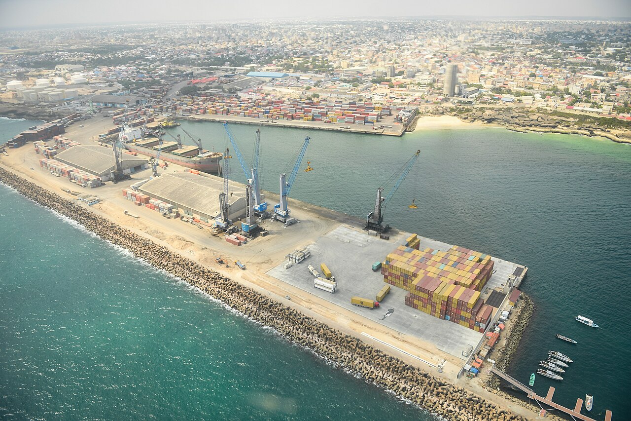 Aerial view of Mogadishu seaport with container cranes, stacked containers and a cargo ship beside the city