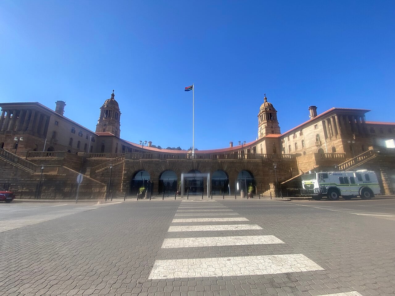 The sandstone Union Buildings in Pretoria with two domed towers and the South African flag under a clear blue sky