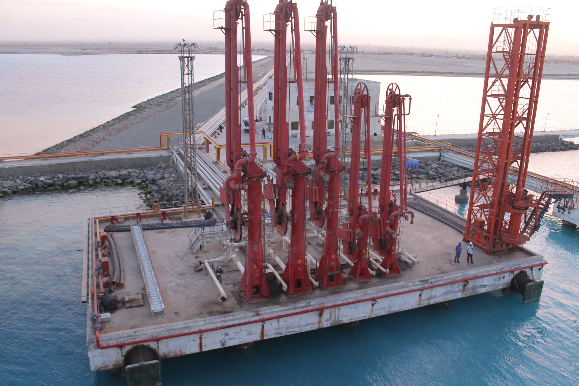 An oil loading jetty with red loading arms on Sudan's Red Sea coast