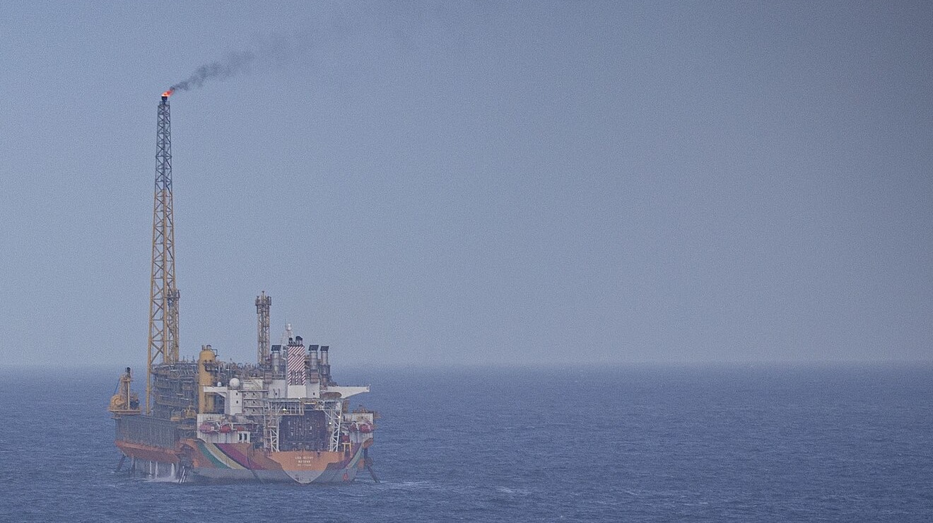 A floating oil production vessel with a lit flare stack on a grey-blue sea off Guyana