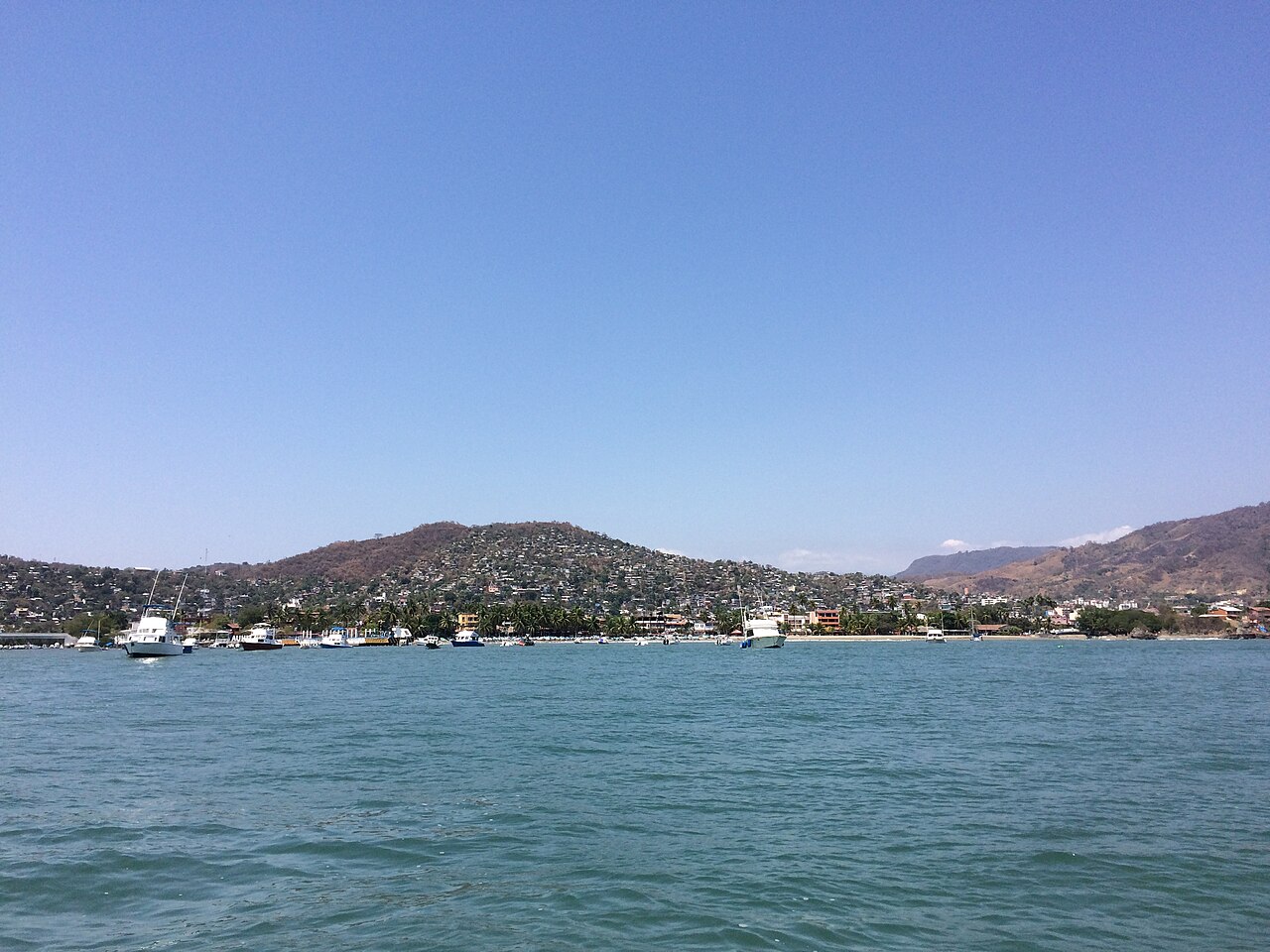 Small boats anchored in Zihuatanejo bay in front of the town and its hills in Guerrero, Mexico