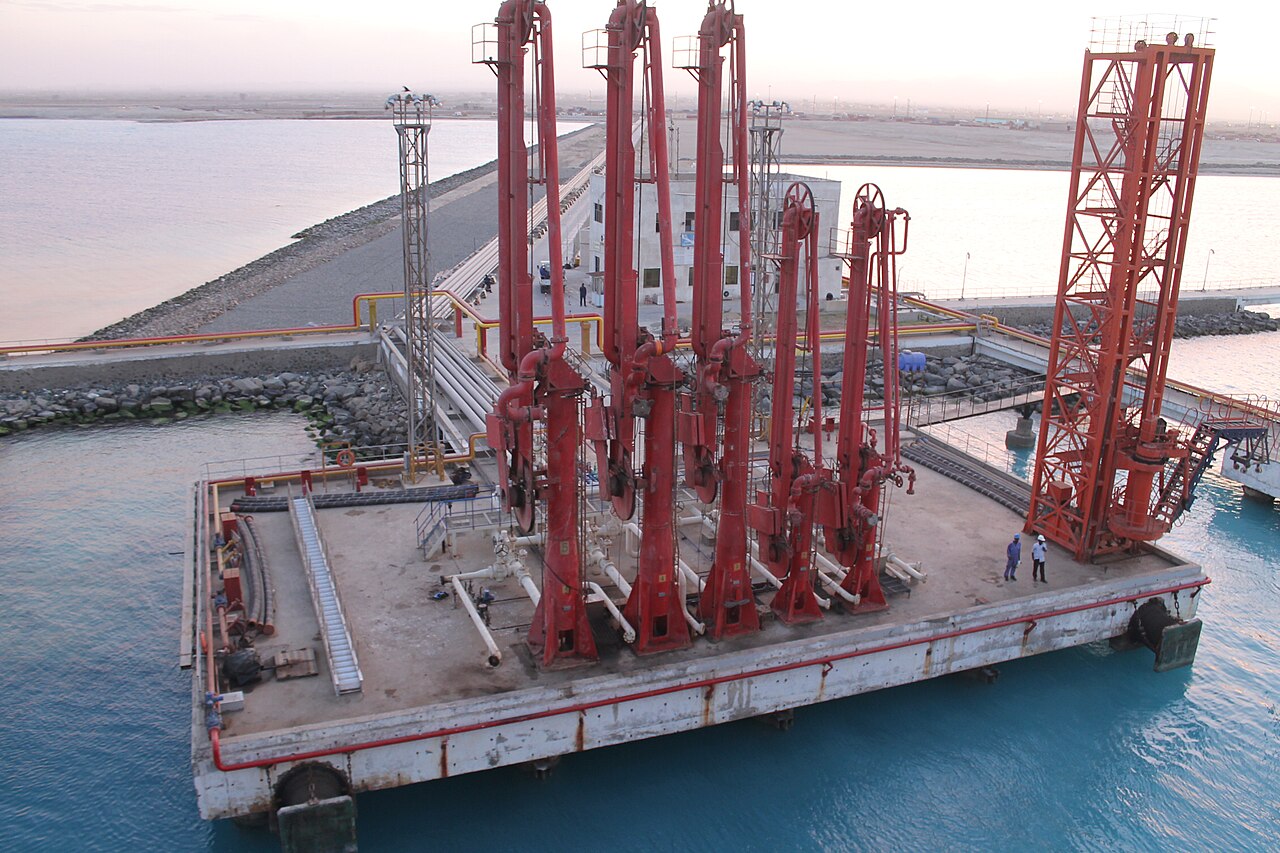 Red loading arms on a cargo pier at a Sudanese port terminal at dusk