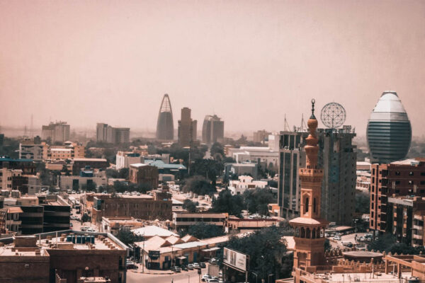 Khartoum skyline under a hazy sky with a minaret, office towers and an egg-shaped glass hotel tower