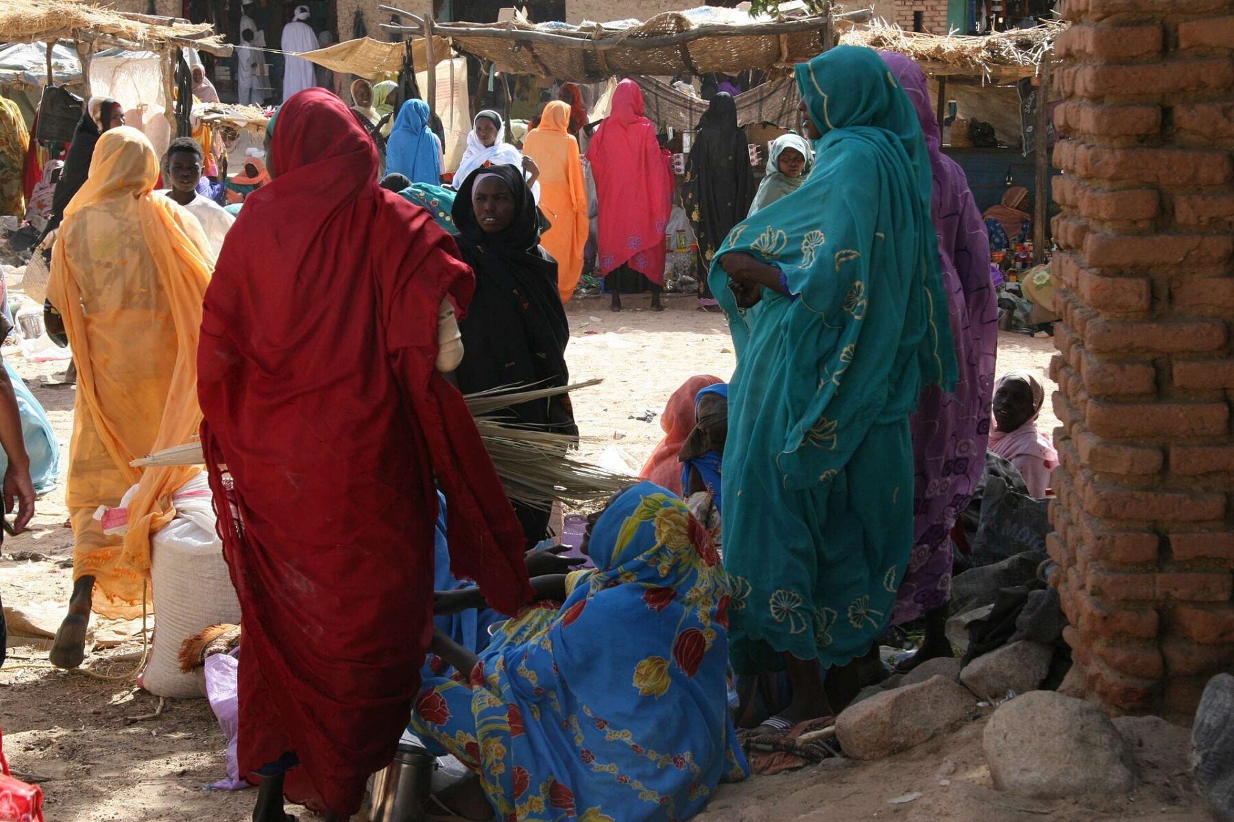 Women in bright headscarves and robes gather among stalls at a market in Darfur, western Sudan, in a 2008 photo