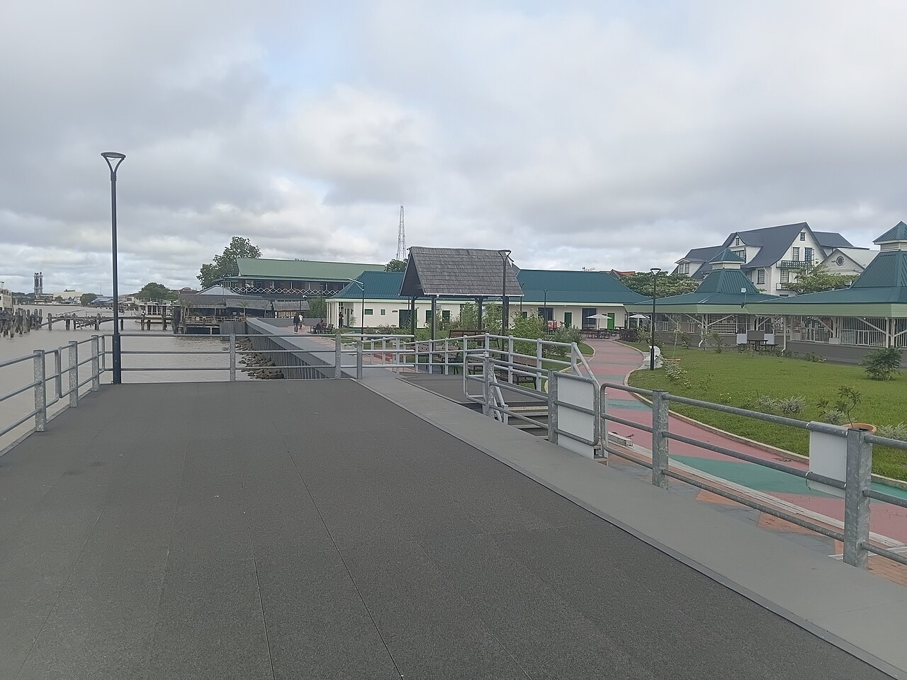 Newly renovated waterfront promenade on the Suriname River in Paramaribo with railings and green-roofed buildings