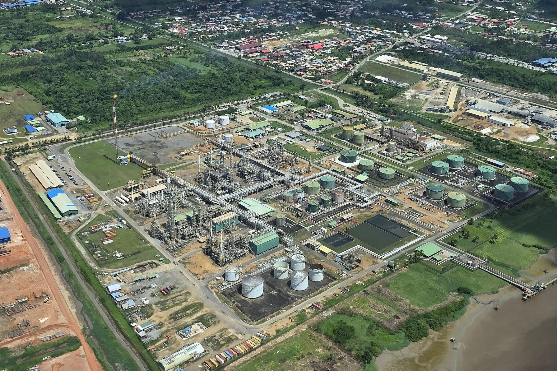 Aerial view of the Staatsolie Tout Lui Faut refinery complex with storage tanks beside the Suriname River