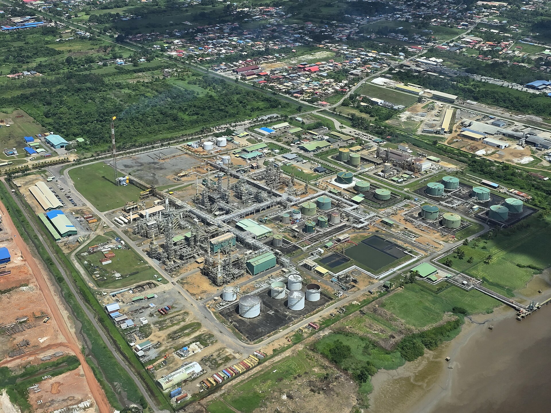 Aerial view of the Staatsolie Tout Lui Faut refinery complex with storage tanks beside the Suriname River