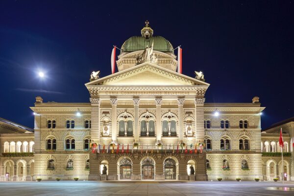The Federal Palace in Bern, seat of the Swiss government and parliament, lit at night with flags on Bundesplatz