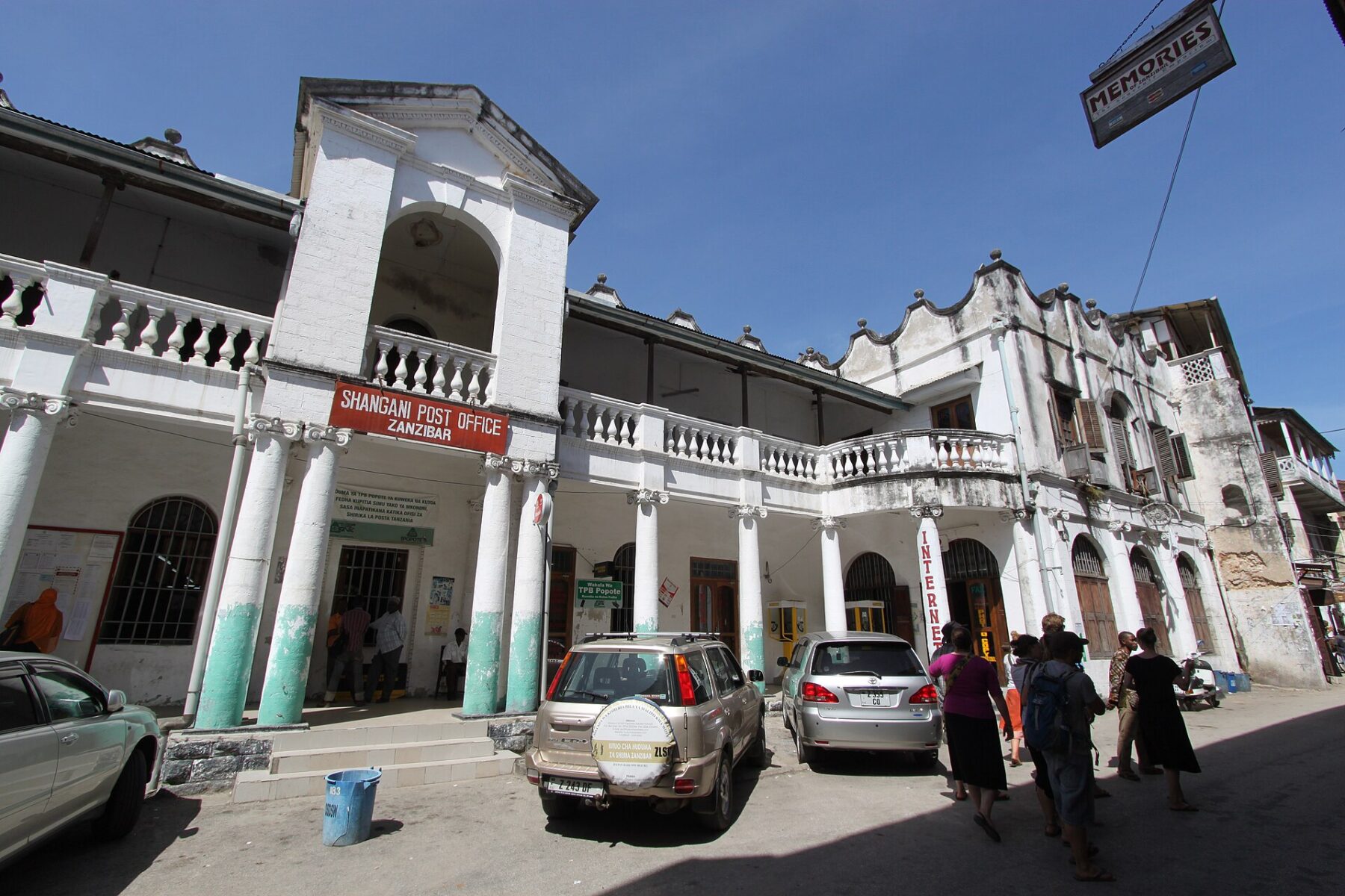 The white colonial-era Shangani Post Office building in Stone Town, Zanzibar, with cars and pedestrians in the street