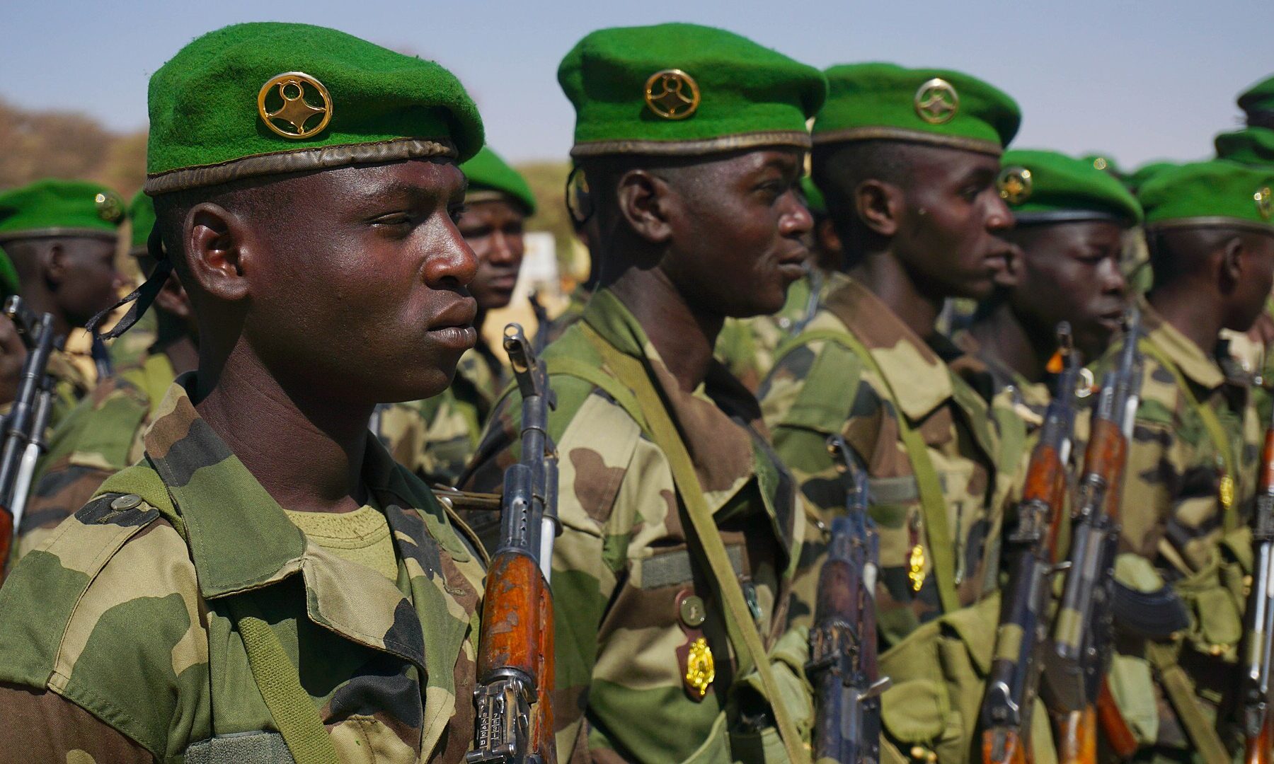 A line of Nigerien soldiers in green berets holding rifles at a parade