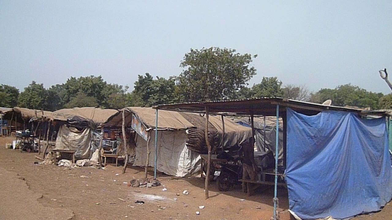 Row of tarpaulin and sheet-metal shelters at an artisanal gold miners' settlement near Gaoua
