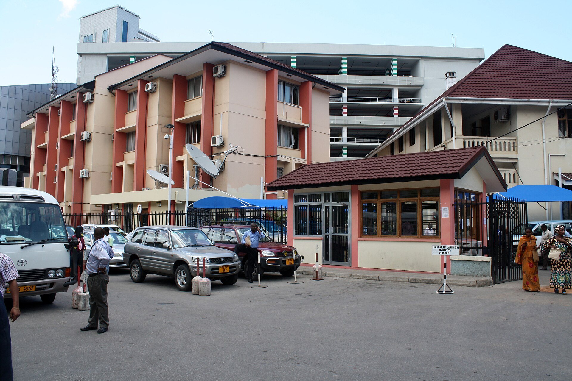 The entrance and guard post of the Ministry of Finance and Economic Affairs offices in Dar es Salaam with parked cars and pedestrians