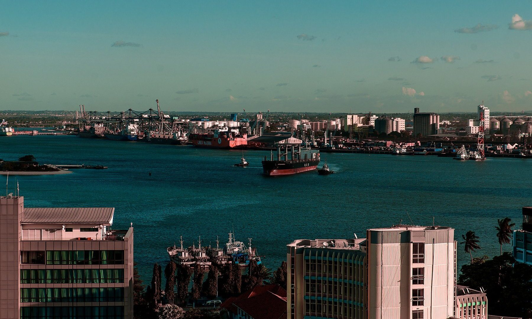 Ship leaving the harbour of Dar es Salaam with the container terminal, fuel tanks and grain silos along the far shore