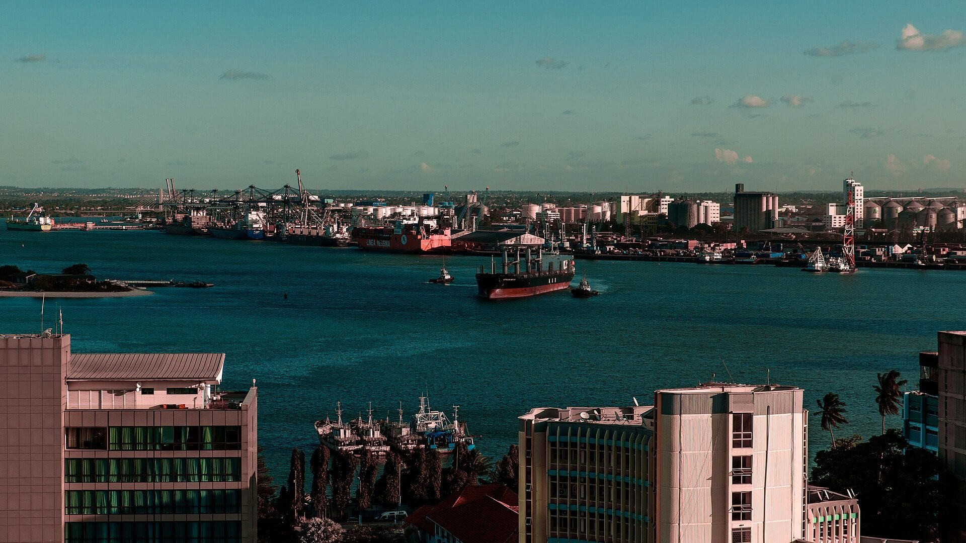 Ship leaving the harbour of Dar es Salaam with the container terminal, fuel tanks and grain silos along the far shore