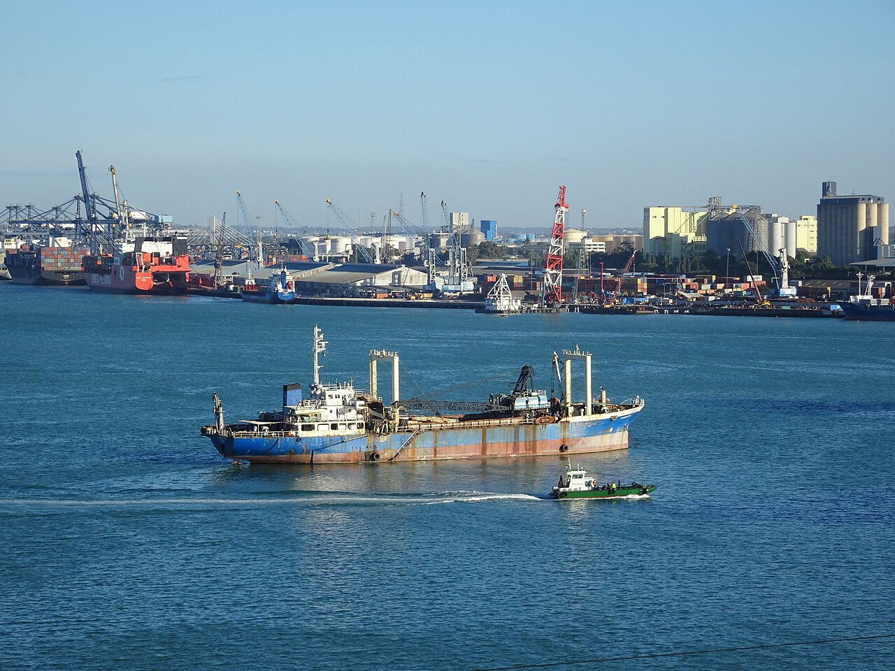 Ships and cranes at the port of Dar es Salaam, with storage tanks and silos along the waterfront