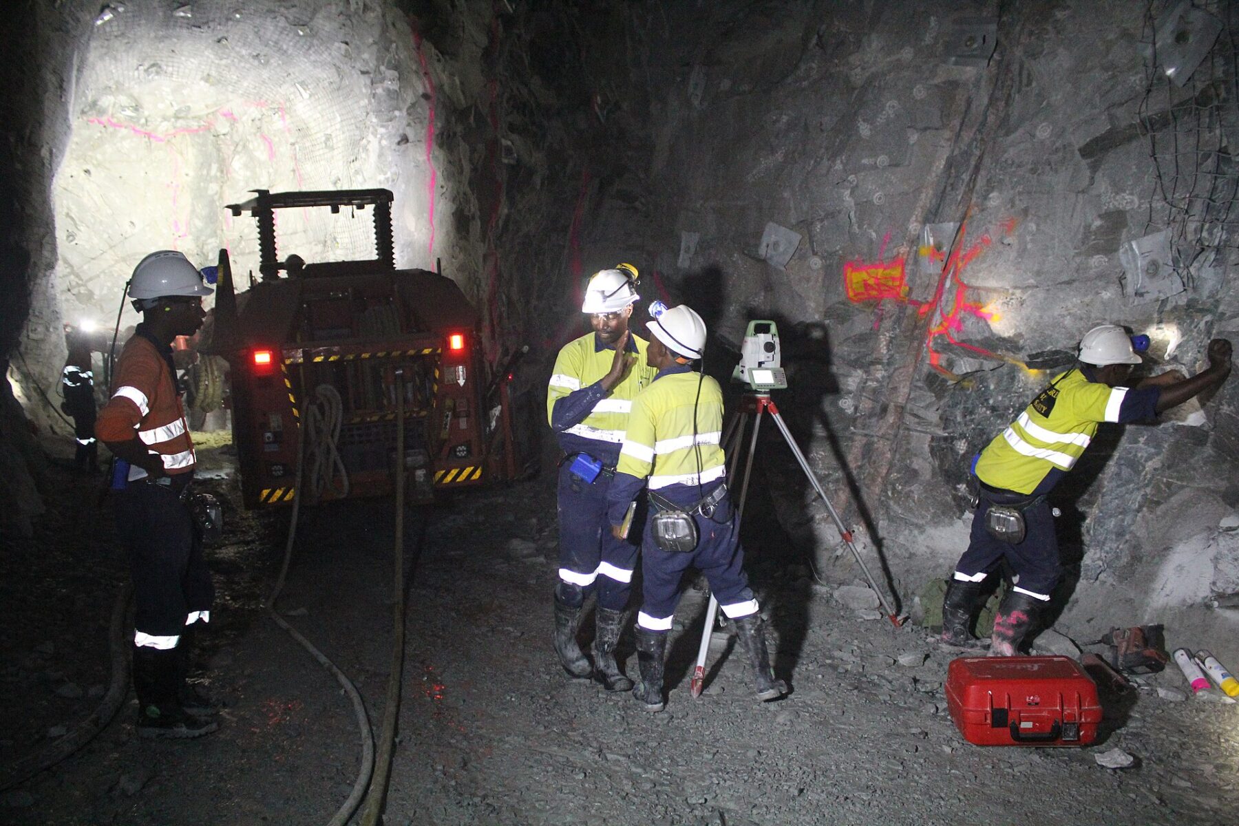 Miners in hard hats and high-visibility clothing prepare a blast in an underground mine tunnel in Tanzania