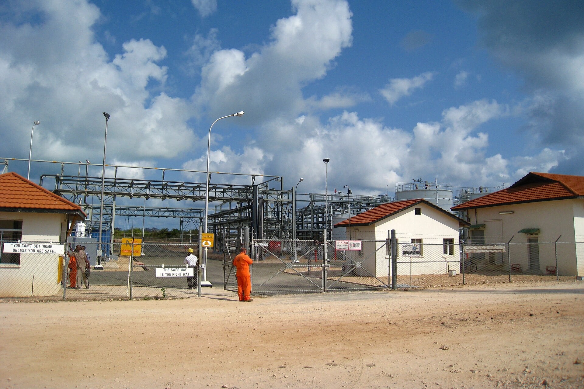 Workers in orange overalls at the gate of the Songo Songo natural gas processing plant in southern Tanzania