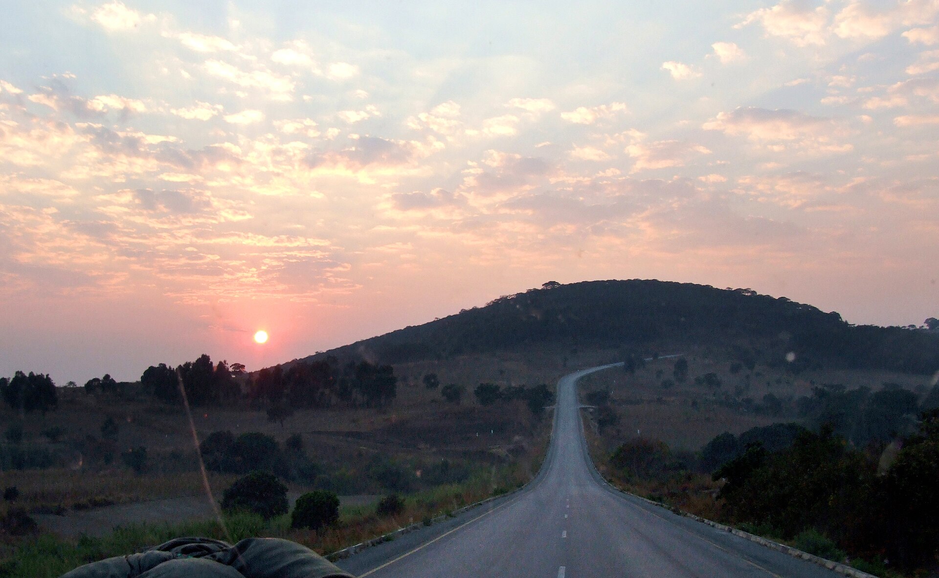 A paved road climbing a hill at sunrise outside Mbeya, Tanzania